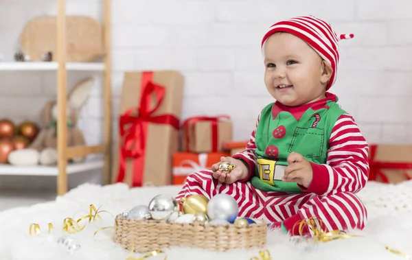 Doce bebê em traje de elfo brincando com decorações de Natal — Fotografia de Stock