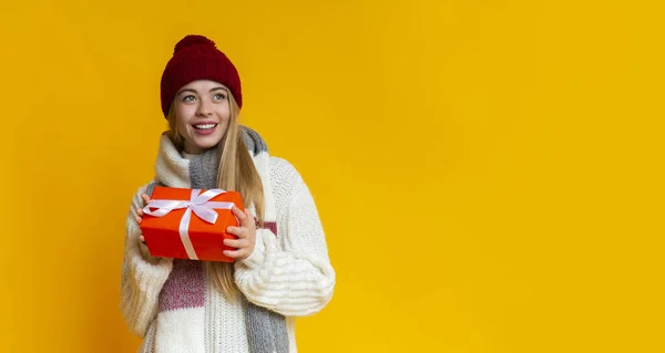 Okouzlující dívka drží vánoční dárek přes žluté pozadí — Stock fotografie
