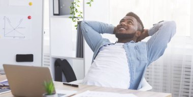 Memnuniyet duyulan ofis çalışanı sandalyeye yaslanıyor, işini bitirdikten sonra dinleniyor.