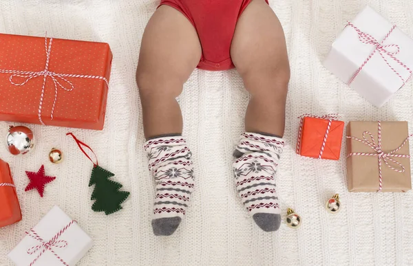 Pernas de criança em meias de inverno de malha com presentes de Natal e decorações — Fotografia de Stock