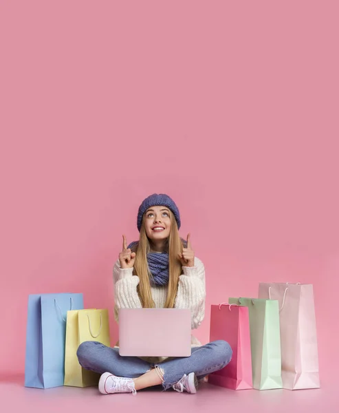 Chica sorprendida con el ordenador portátil de color rosa apuntando hacia arriba en el espacio vacío —  Fotos de Stock