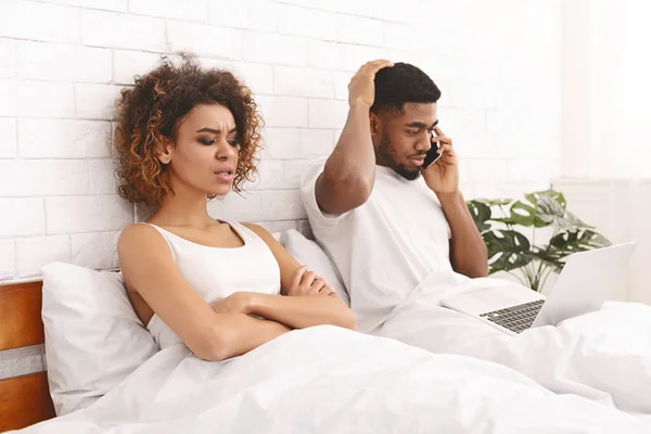 Beledigd afrikaanse vrouw liggend in bed met haar praten op telefoon echtgenoot — Stockfoto