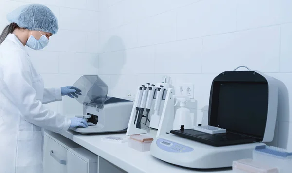 Mujer joven que trabaja en un laboratorio moderno y utiliza el analizador — Foto de Stock