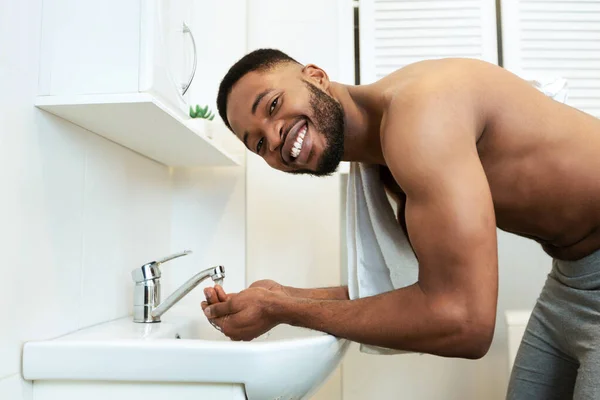Shirtless africano millennial hombre lavándose la cara en el baño — Foto de Stock