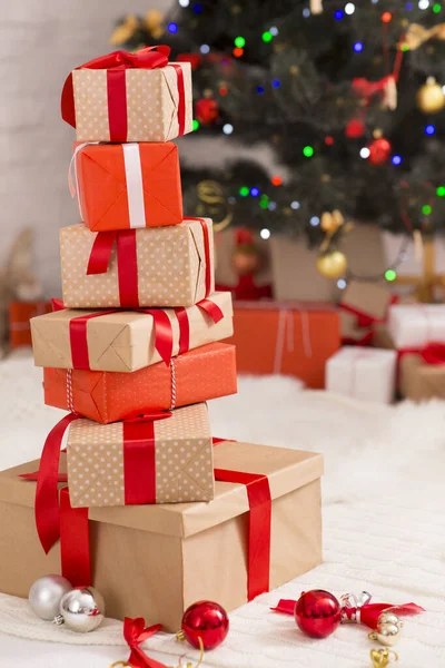 Pilha de caixas de presente embrulhadas perto da árvore de Natal em casa — Fotografia de Stock
