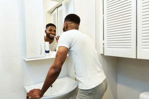 Hombre afroamericano cepillándose los dientes en el baño — Foto de Stock