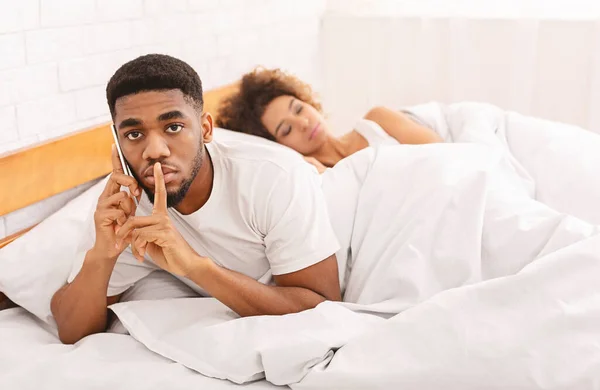 Negru trișor om vorbind privat pe telefonul mobil în pat de familie — Fotografie, imagine de stoc