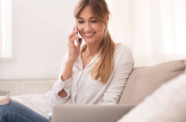 Evdeki koltukta oturan neşeli bayan cep telefonuyla konuşuyor.