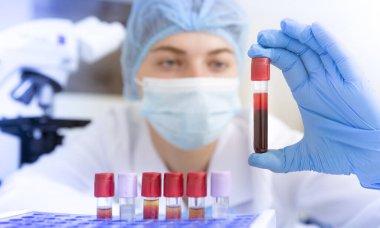 Genç ve çekici kadın bilim adamı elinde kırmızı maddeli test tüpü tutuyor.