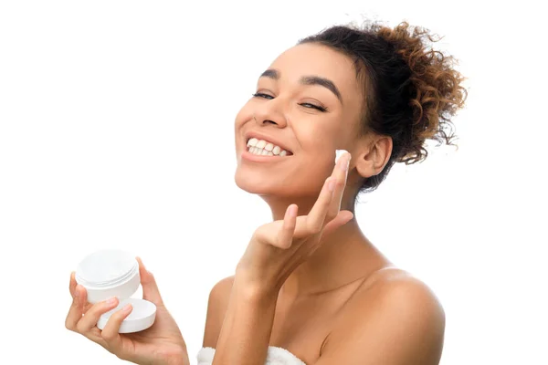 Conceito de cuidados com a pele. Menina afro aplicando creme na bochecha — Fotografia de Stock