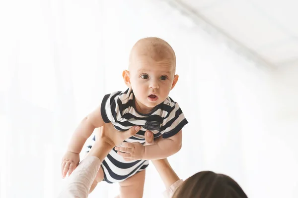 Mulher irreconhecível levantando bebê pequeno bonito no ar — Fotografia de Stock