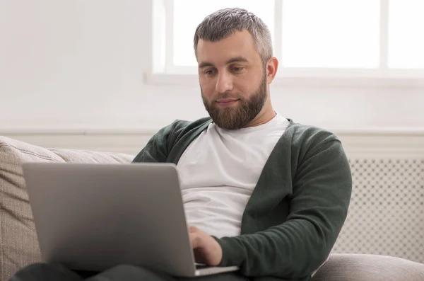 Uomo serio che lavora sul computer portatile online a casa — Foto Stock