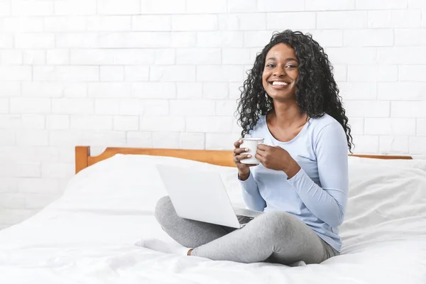 Feliz joven mujer coqueteando en línea en el ordenador portátil en la cama — Foto de Stock