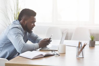 İş yerinde akıllı telefon kullanan zenci bir ofis çalışanı.