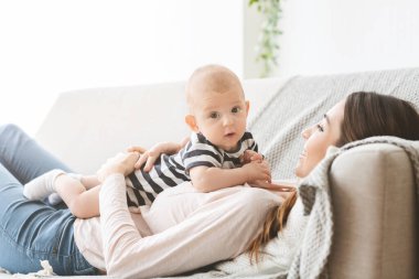 Sevimli yeni doğmuş bebek annesiyle kanepede dinleniyor.