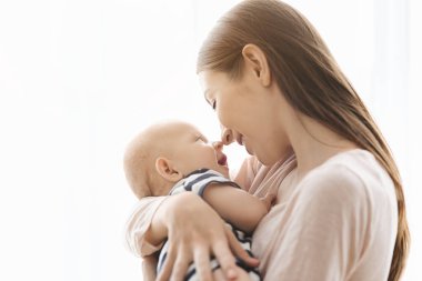 Mutlu anne küçük bebeğiyle burunlarına dokunuyor.