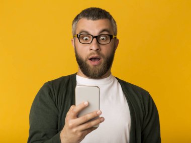 Gözleri açık cep telefonuna bakan hayret verici bir adam.