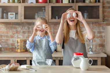 Anne ve kızı yemek yaparken yumurta gözlüğü yapıyorlar.