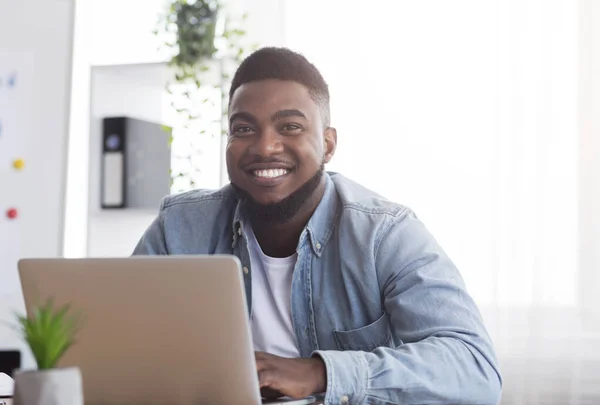Portret van een lachende Afrikaanse werknemer op het werk in een modern kantoor — Stockfoto