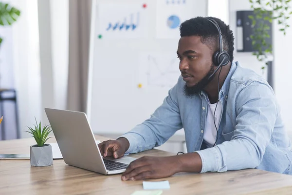Zwarte customer support manager met headset met laptop op kantoor — Stockfoto