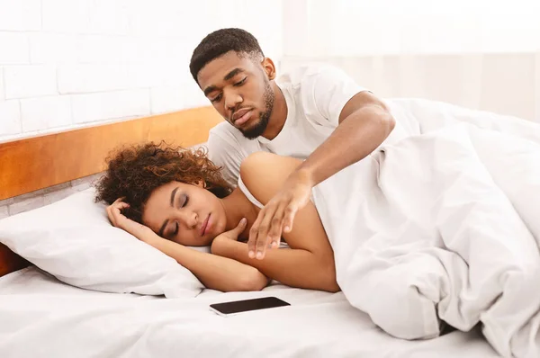 Verdachte Afrikaan die zijn slapende vrouw mobiele telefoon controleert in bed — Stockfoto