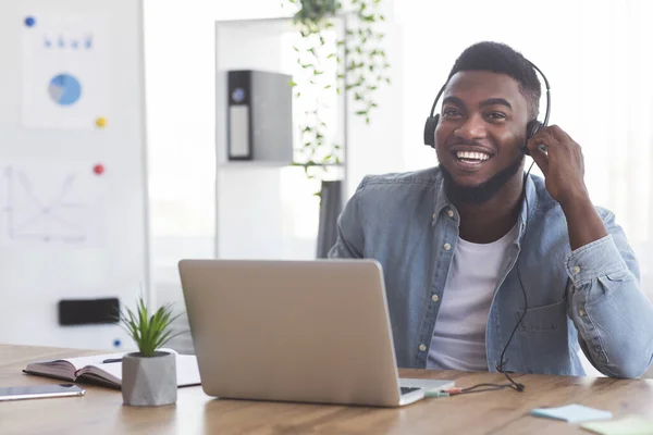 Usmívající se zaměstnanec ve sluchátkách sledující webinář na notebooku v kanceláři — Stock fotografie