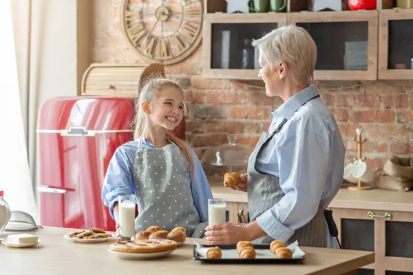 Positiva niña almorzando con su abuela en la cocina —  Fotos de Stock