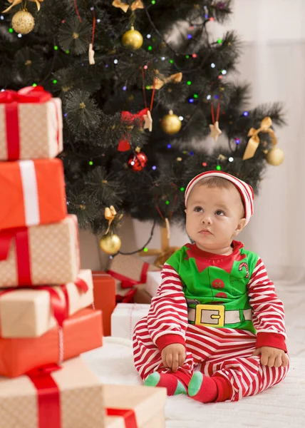 Úžasný malý elf při pohledu na spoustu dárkových krabic, sedí v blízkosti vánoční strom — Stock fotografie