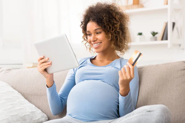 Opgewonden zwangere vrouw koopt goederen voor pasgeborenen, met behulp van tablet — Stockfoto