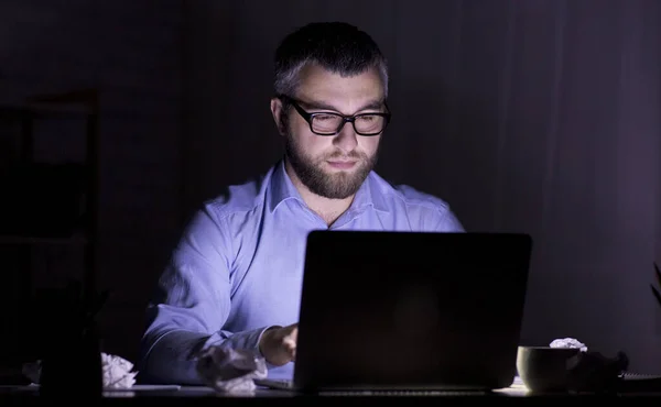 Homem perplexo olhando para a tela do laptop no quarto escuro — Fotografia de Stock