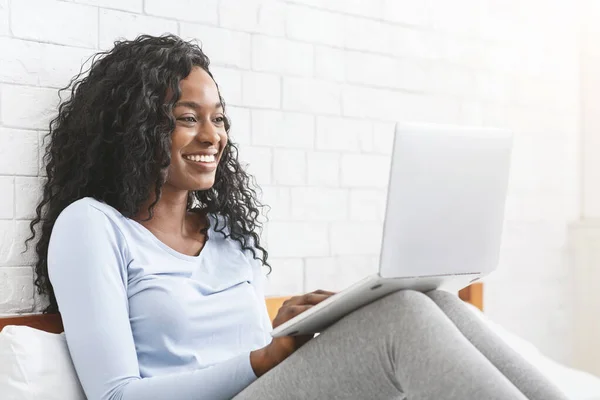 Happy young afro lady chatting online in bedroom — Stock Photo, Image