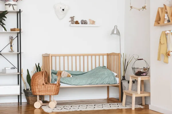 Interior del dormitorio del bebé con acogedora cama de madera y cochecito de mimbre — Foto de Stock