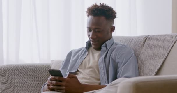 Africain américain gars regarder des vidéos sur téléphone mobile — Video