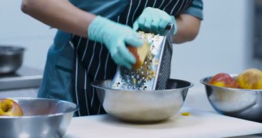 Kadın el, mutfakta salata için elma rendeliyor.