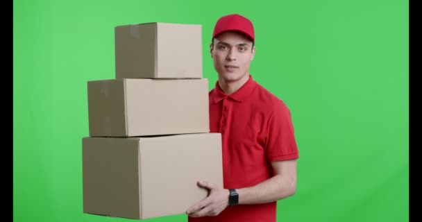 Przyjazny dostawca z stosem pudełek uśmiechniętych do kamery — Wideo stockowe