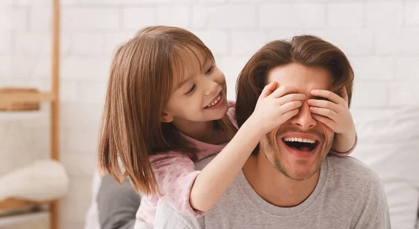 Doce menina brincalhão cobrindo seus olhos pai — Fotografia de Stock