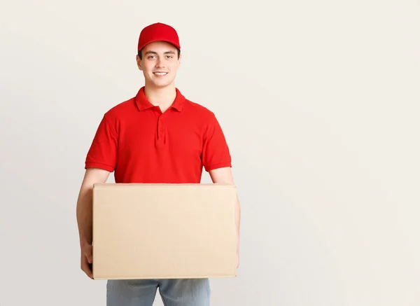 Arbeit des modernen Postboten. Lächelnder junger Mann in Uniform mit großem Karton — Stockfoto