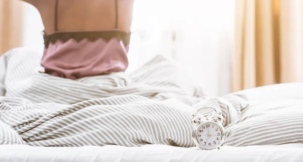 Afro-américaine fille réveillée, assise sur le lit, regardant fenêtre et réveil — Photo