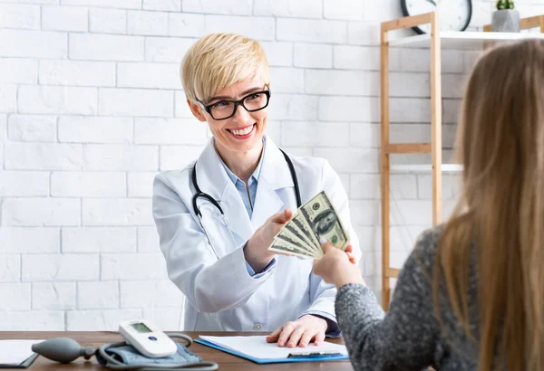 Corruption concert. Doctor takes money from hands of patient in office — Stock Photo, Image