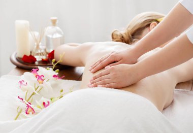 Spa günü. Kız masadaki çiçekler ve yağla masaj yaptırıyor.