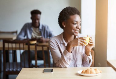Milenyum Afrikalı Amerikalı kız rahat bir kafede bir fincan kahveyle rahatlıyor.