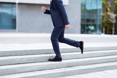 Resmi takım elbiseli işadamının ofis binasının yakınındaki merdivenlerde koşması.