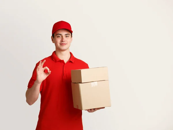 Amistoso mensajero sostiene cajas de cartón y muestra gesto bien — Foto de Stock
