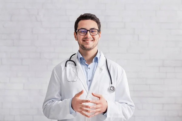 Trabajo remoto. Joven médico en bata blanca sobre fondo de pared de ladrillo — Foto de Stock