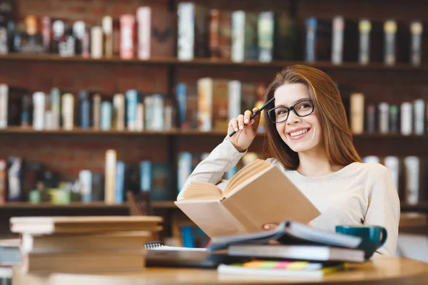 Jonge lachende vrouw studeert met veel boeken thuis — Stockfoto