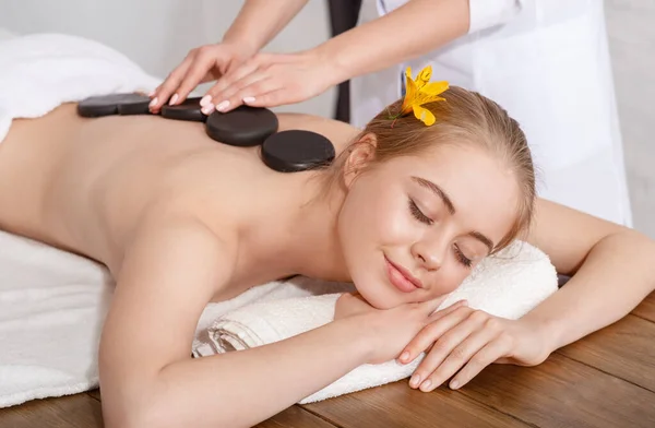 Menina com olhos fechados recebe massagem de pedra quente — Fotografia de Stock