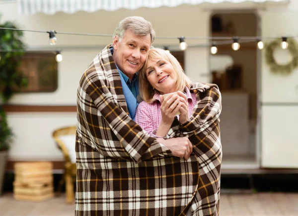 Прекрасна старша пара обнімається під теплим ковдрою і обіймає один одного на кемпінгу — стокове фото