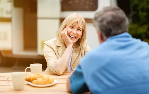 Starší žena mluví se svým manželem během chutné snídaně s kávou a croissanty v kempu — Stock fotografie