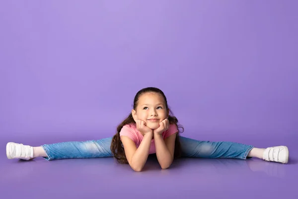 Schattig klein meisje maken splitst op paarse achtergrond — Stockfoto