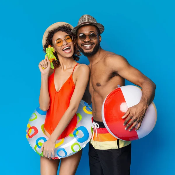 Divertimento estivo. Allegro coppia nera in costumi da bagno godendo di estate con giocattoli gonfiabili — Foto Stock